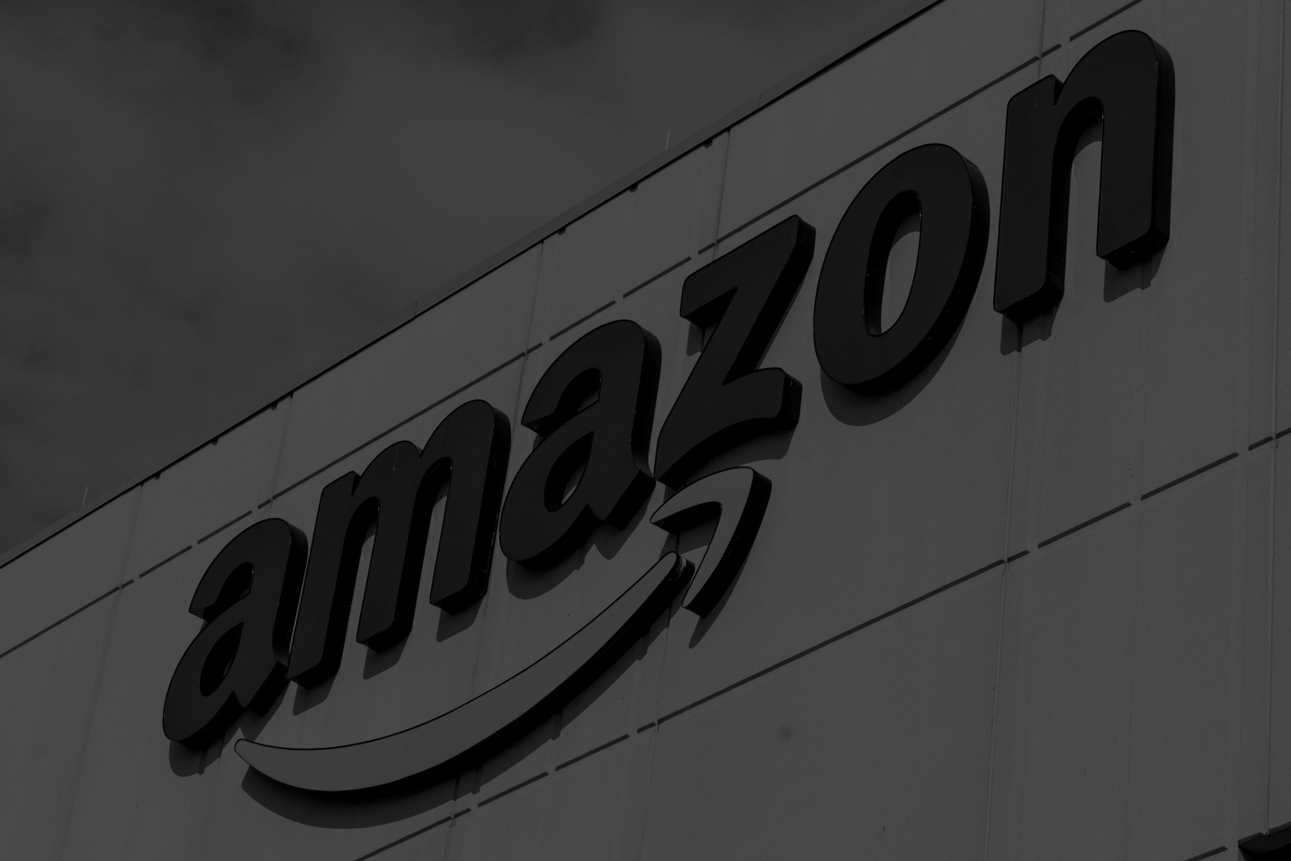 Amazon logo on a fulfillment and e-commerce facility building, illustrating Amazon Prime Day, online shopping, consumer technology retail, affiliate commerce, and product discovery.