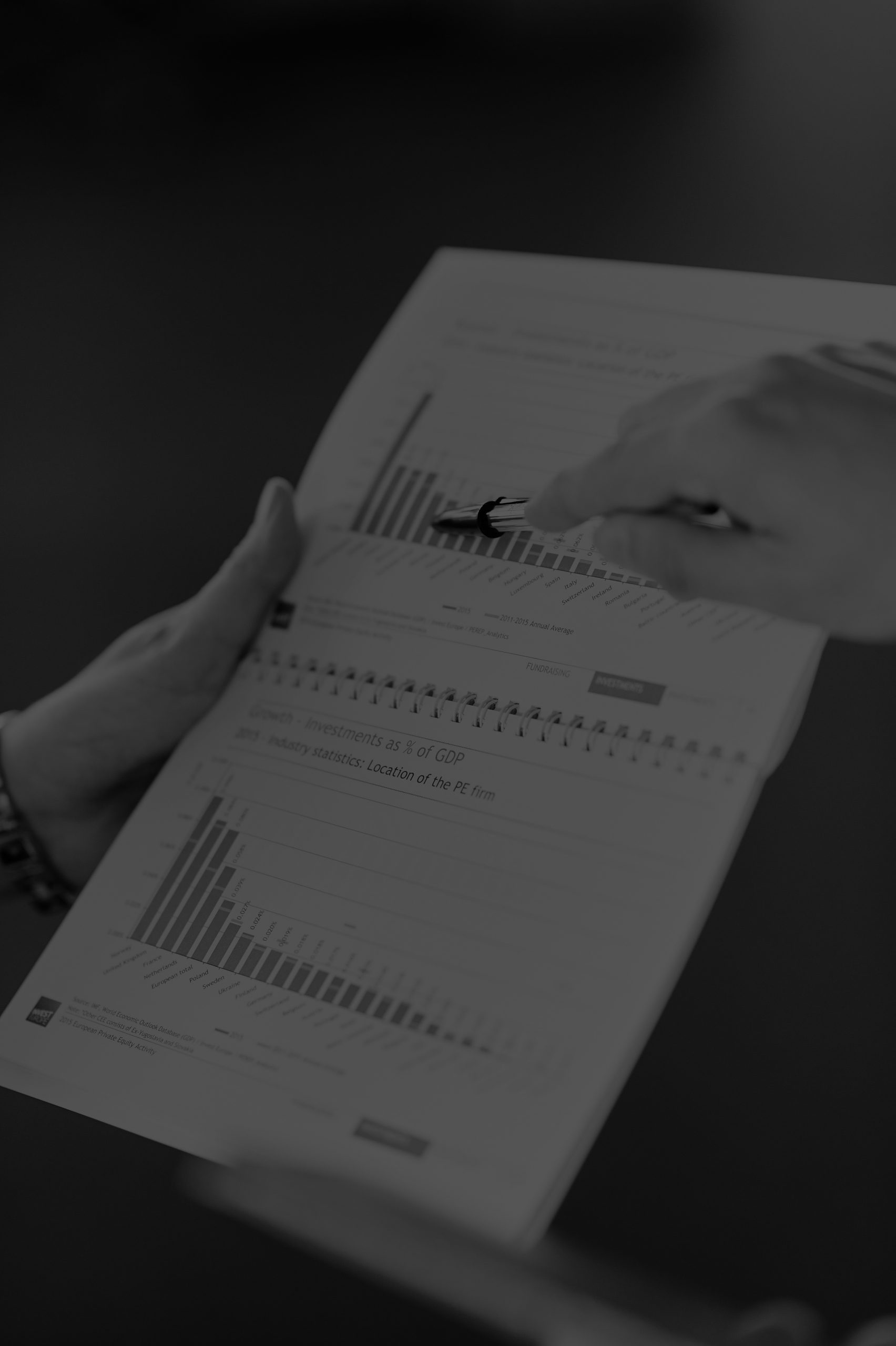 Hands reviewing consumer research charts and survey data illustrating U.S. consumer trust, technology purchasing behavior, and manufacturing perceptions.