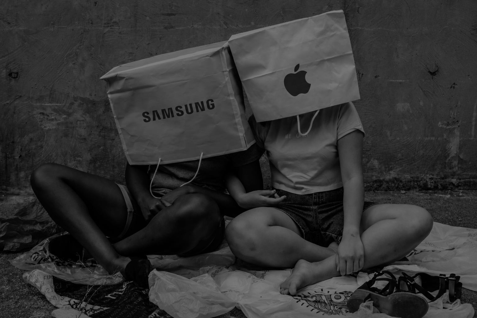 Black-and-white image of people wearing Samsung and Apple bags over their heads, illustrating why AI models cite some consumer tech brands and ignore others.