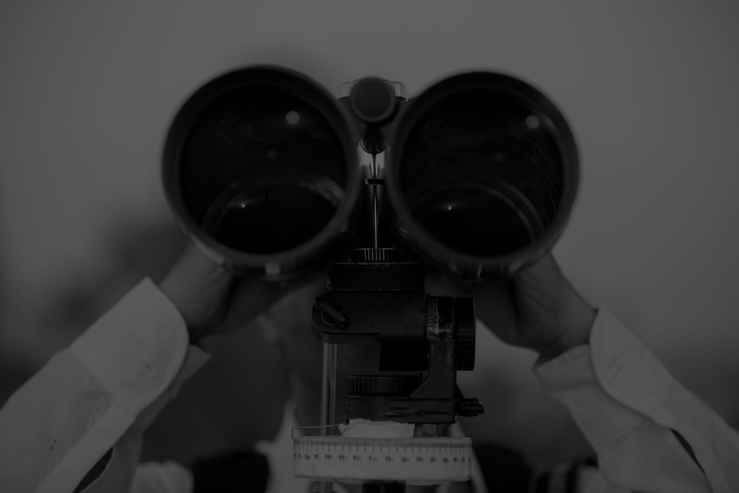 Black-and-white image of a person looking through binoculars, representing a well-known company struggling to be found in AI search.